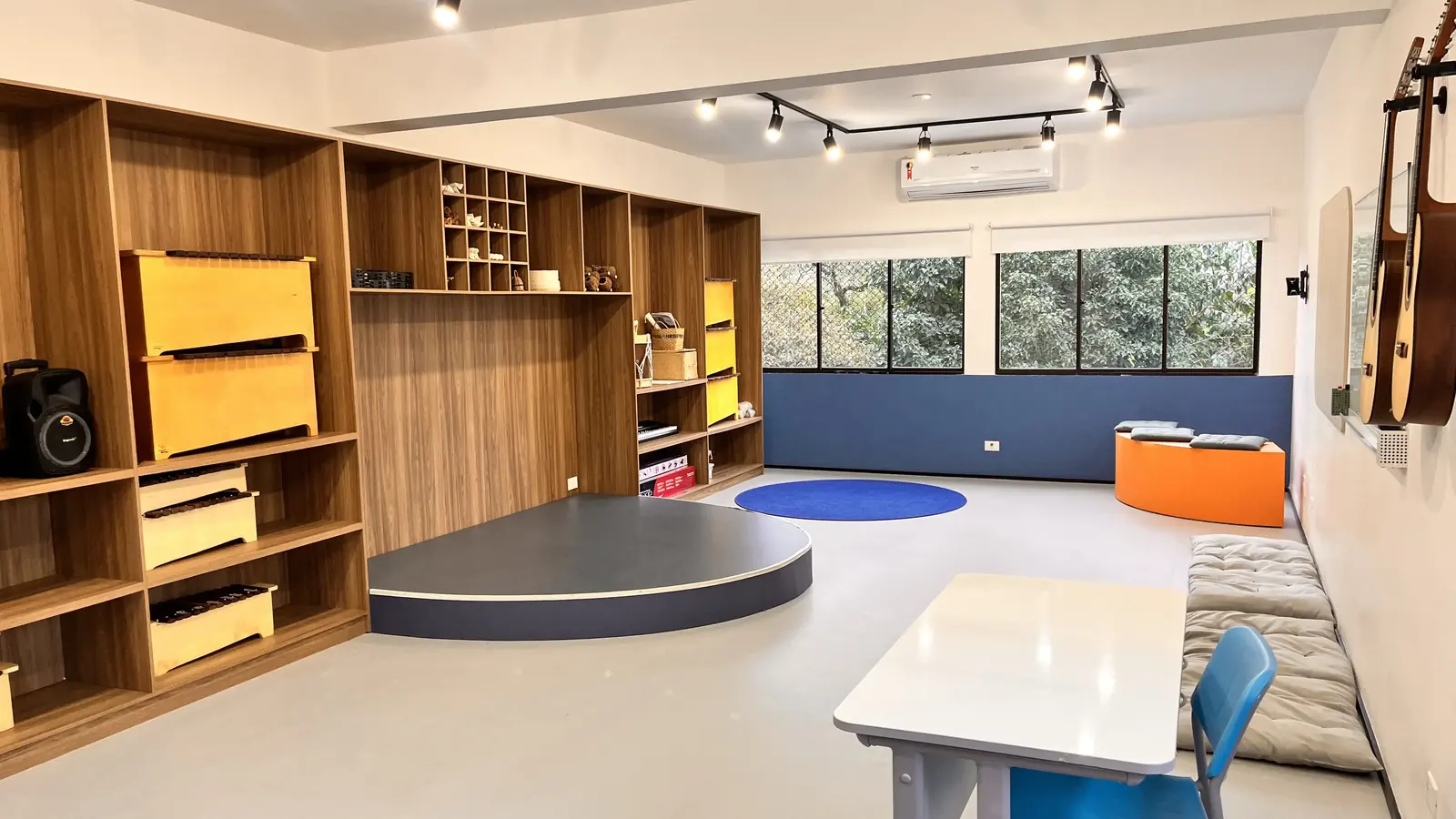 Sala de música com instrumentos nas estantes, violões na parede e um pequeno palco circular.